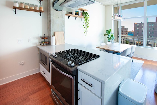kitchen with appliances with stainless steel finishes, open shelves, wood finished floors, a chandelier, and white cabinets