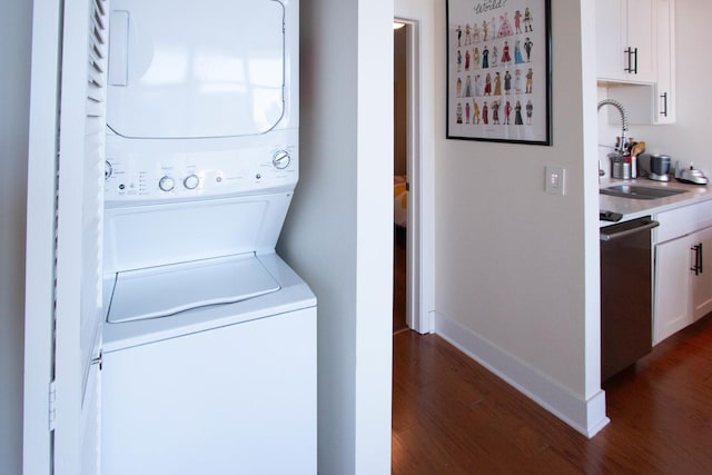 laundry room featuring stacked washer / dryer, dark wood finished floors, and baseboards