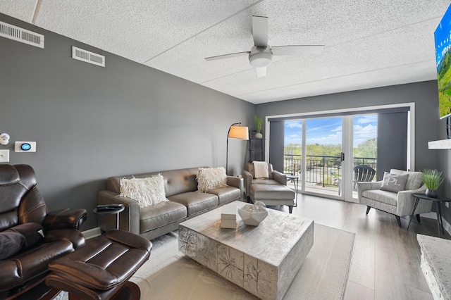 living area featuring ceiling fan, wood finished floors, and a textured ceiling