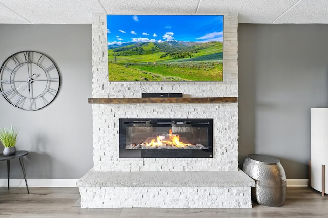 detailed view of a fireplace, wood finished floors, and baseboards