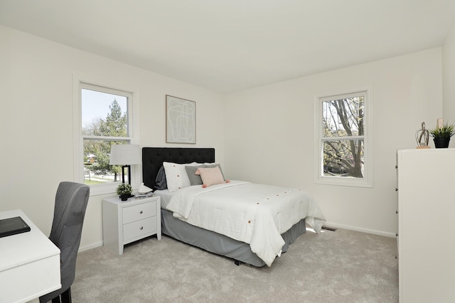 bedroom featuring multiple windows, light colored carpet, and baseboards