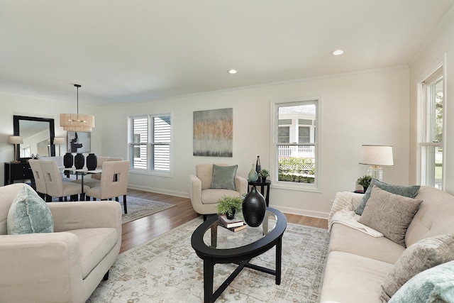 living room featuring plenty of natural light, baseboards, wood finished floors, ornamental molding, and recessed lighting