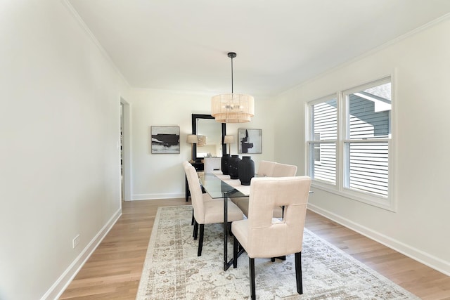dining area with a chandelier, ornamental molding, light wood finished floors, and baseboards
