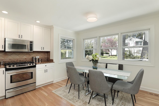 kitchen with appliances with stainless steel finishes, healthy amount of natural light, light wood-type flooring, crown molding, and recessed lighting