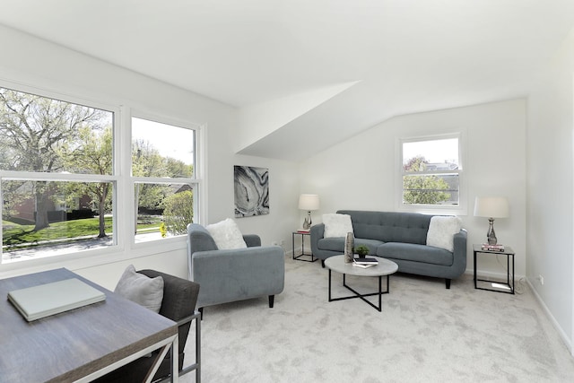living area with light colored carpet, vaulted ceiling, and baseboards