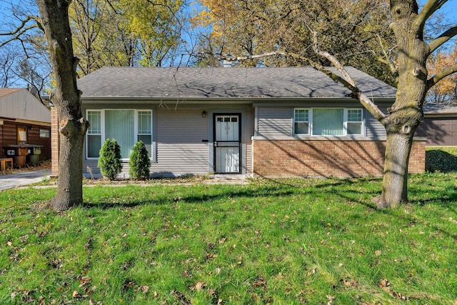 ranch-style home featuring a front yard, brick siding, and a shingled roof