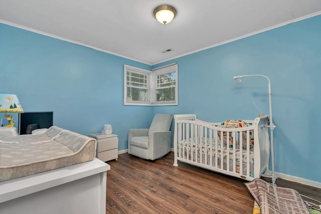 bedroom with baseboards, crown molding, and wood finished floors