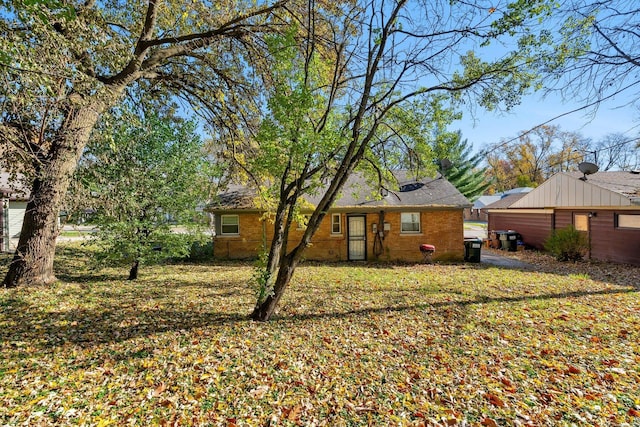 rear view of house featuring brick siding and a lawn
