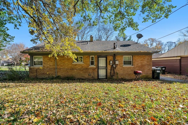 back of house with brick siding and a shingled roof