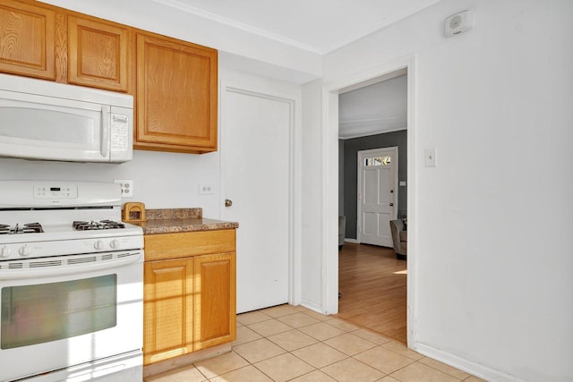 kitchen with white appliances, light tile patterned flooring, and ornamental molding