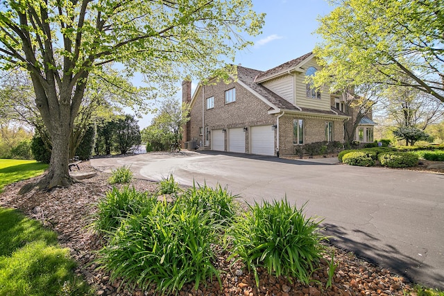 15521 S Mallard Ln, Homer Glen, IL 60491 - view of home's exterior with a garage, a chimney, cooling unit, driveway, and brick siding