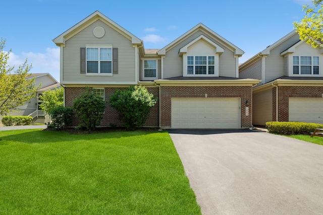 view of front of house with an attached garage, asphalt driveway, a front lawn, and brick siding
