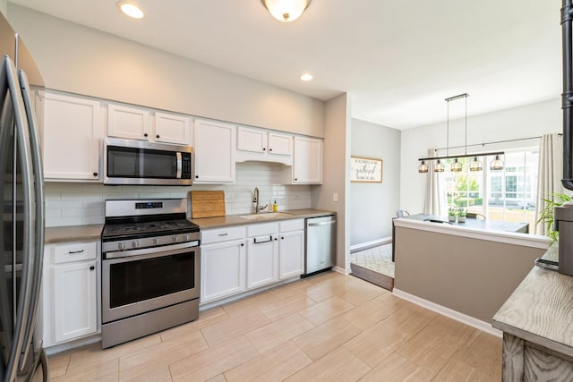 kitchen featuring stainless steel appliances, a sink, backsplash, white cabinetry, and recessed lighting