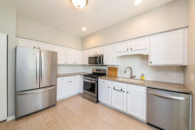 kitchen featuring stainless steel appliances, a sink, white cabinets, and recessed lighting