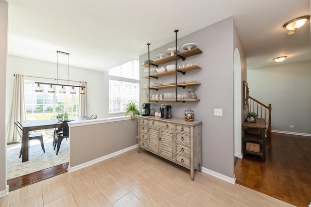 hallway with baseboards, arched walkways, and light wood-type flooring