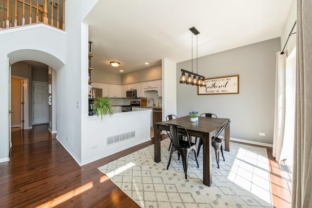 dining room with arched walkways, light wood-type flooring, baseboards, and recessed lighting