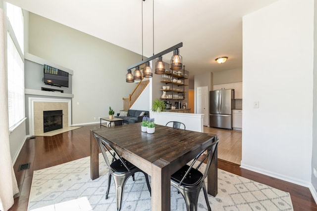 dining space with wood finished floors, stairway, baseboards, and a tile fireplace