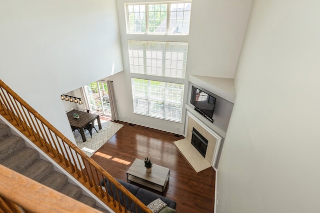 living room with wood finished floors, a towering ceiling, stairway, a fireplace, and baseboards