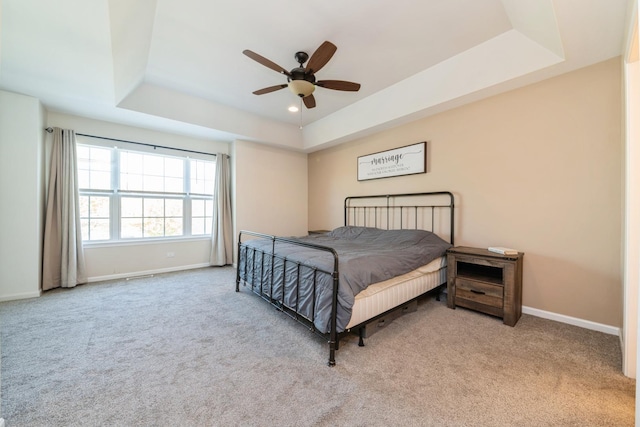 bedroom with a tray ceiling, carpet, baseboards, and ceiling fan