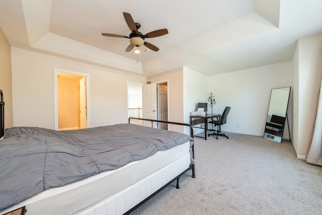carpeted bedroom with a raised ceiling, a ceiling fan, baseboards, and an office area