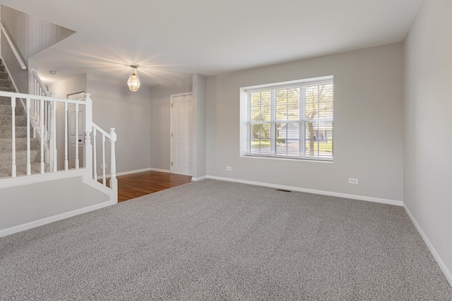carpeted spare room with stairway and baseboards
