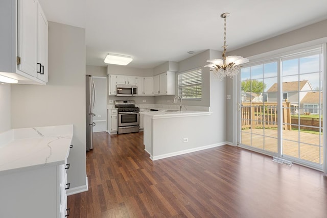 kitchen featuring stainless steel appliances, dark wood-style flooring, a chandelier, a sink, and white cabinetry