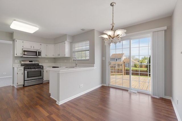 kitchen with stainless steel appliances, a chandelier, light countertops, dark wood-type flooring, and a sink