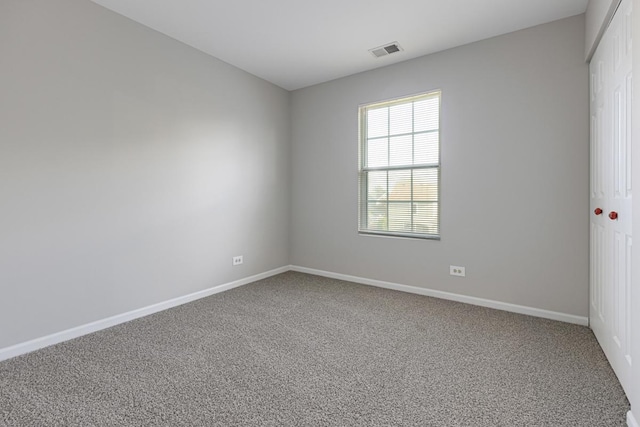 spare room featuring carpet floors and baseboards