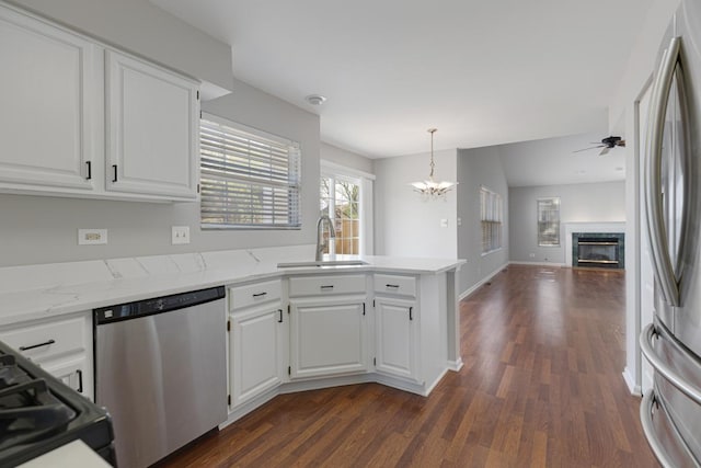 kitchen with appliances with stainless steel finishes, a sink, a peninsula, a chandelier, and dark wood-type flooring