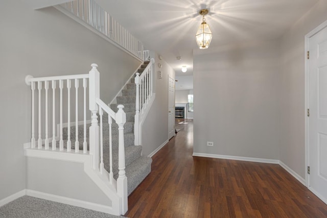 entrance foyer with stairs, wood finished floors, baseboards, and a chandelier