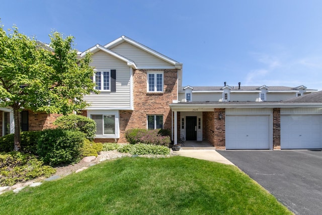 view of front of house featuring brick siding, a front lawn, asphalt driveway, and a garage