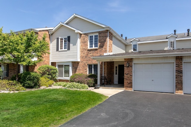 view of front of property with brick siding, a front yard, and asphalt driveway