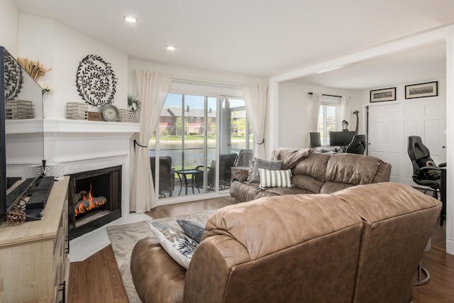 living room with a fireplace with flush hearth, recessed lighting, wood finished floors, and a water view