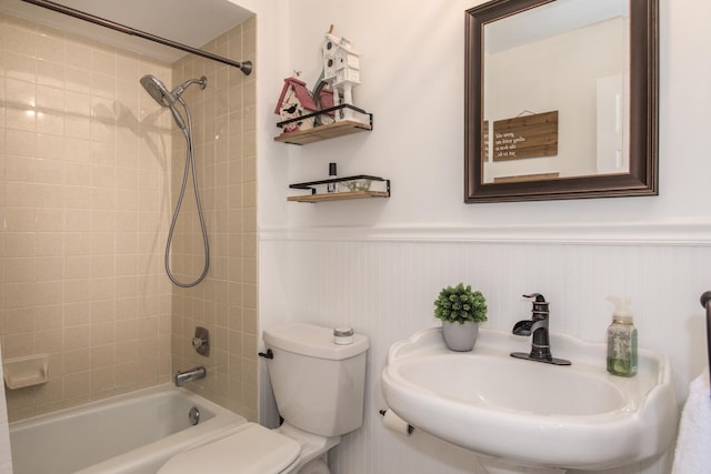 full bath with a sink, toilet, a wainscoted wall, and tub / shower combination