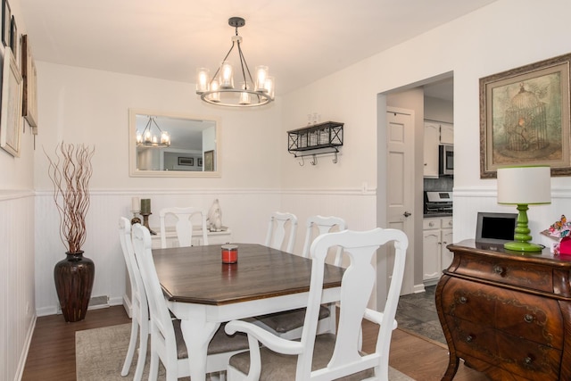 dining room featuring a chandelier, a wainscoted wall, and dark wood finished floors