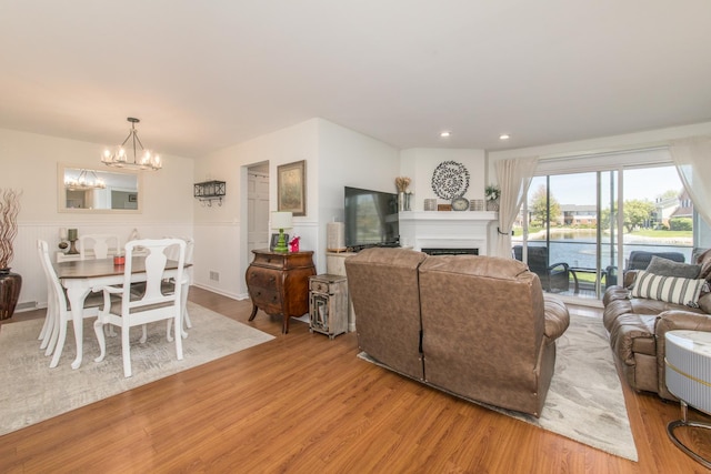 living room with a chandelier, wood finished floors, a fireplace, wainscoting, and recessed lighting