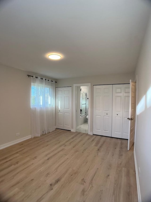 2508 Mitchell Dr, Woodridge, IL 60517 - unfurnished bedroom featuring baseboards, light wood-type flooring, two closets, and ensuite bath
