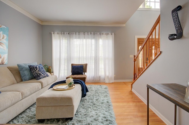 living area featuring light wood-style floors, stairway, baseboards, and ornamental molding