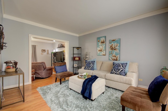 living room with ornamental molding, light wood-style flooring, and baseboards