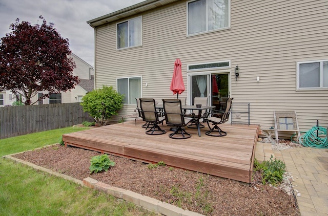 back of property with outdoor dining space, fence, and a wooden deck