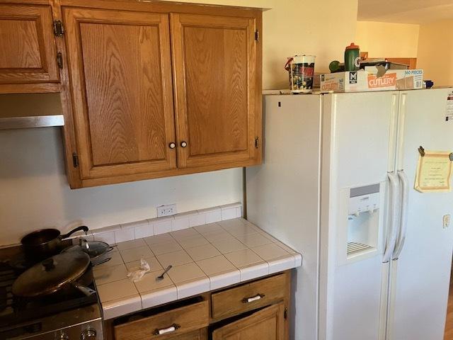 1336 Ardmore Dr, Round Lake Beach, IL 60073 - kitchen featuring white fridge with ice dispenser, tile counters, and brown cabinets