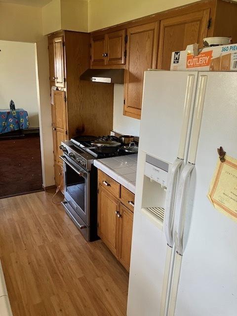 1336 Ardmore Dr, Round Lake Beach, IL 60073 - kitchen with white fridge with ice dispenser, stainless steel gas stove, tile countertops, and brown cabinets