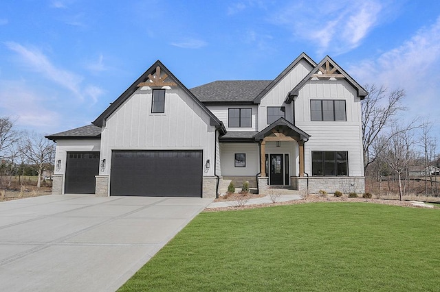 modern farmhouse featuring board and batten siding, stone siding, a front yard, driveway, and a garage