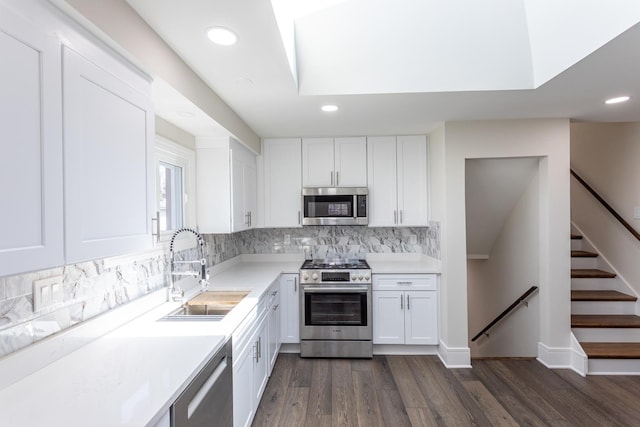 kitchen featuring stainless steel appliances, a sink, recessed lighting, white cabinets, and dark wood-style floors