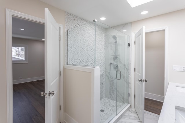 bathroom featuring a marble finish shower, recessed lighting, baseboards, and a sink