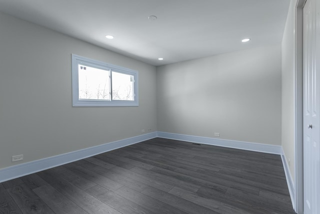 empty room featuring dark wood-type flooring, baseboards, and recessed lighting