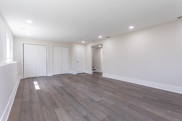 unfurnished bedroom with two closets, dark wood-type flooring, baseboards, and recessed lighting