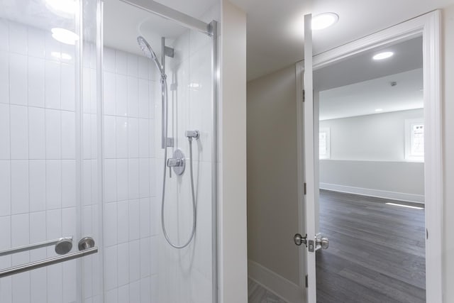 full bathroom with a shower stall, baseboards, and wood finished floors