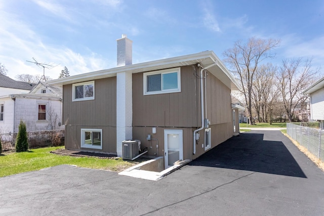 rear view of property with a chimney, fence, and central air condition unit