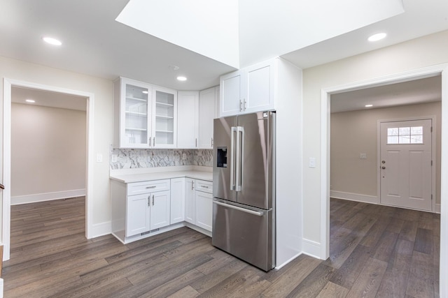 kitchen with stainless steel fridge, white cabinetry, light countertops, dark wood-style flooring, and glass insert cabinets
